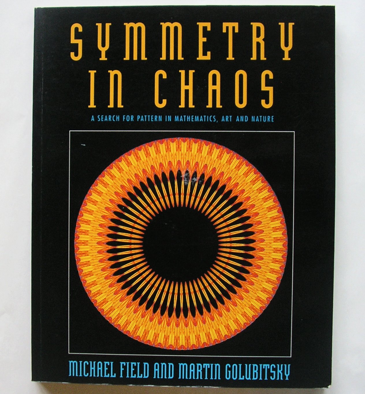 A radial orange and yellow flame-like pattern forming a symmetrical ring on a black ground, with sharp elongated shapes radiating from a central black circle.