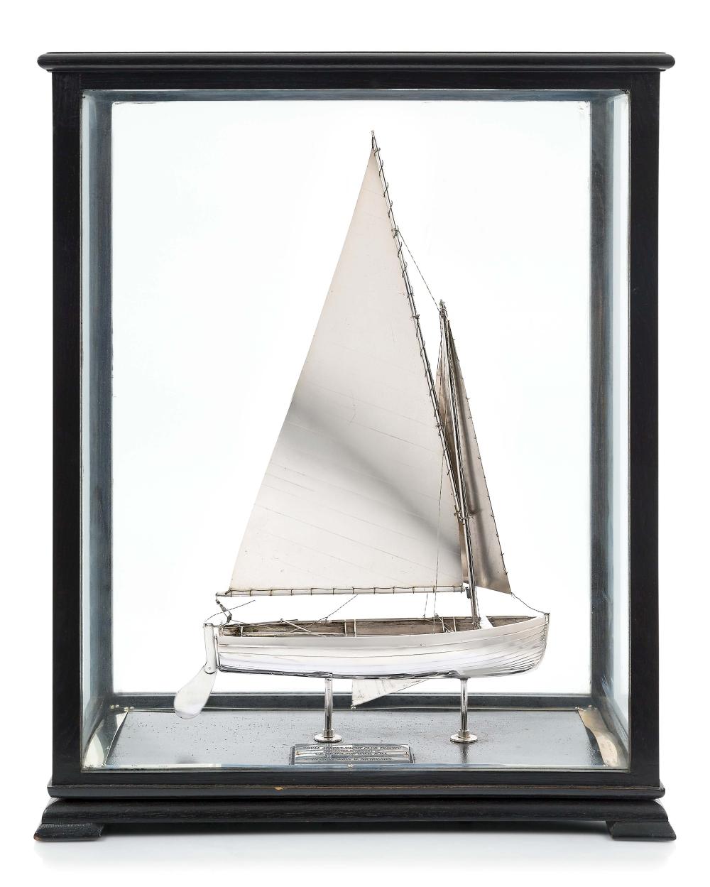 A silver model yacht in a glass case