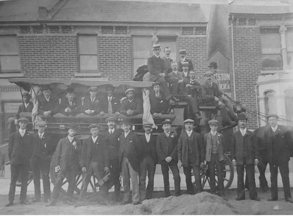 A large group of men posing with a horse-drawn charabanc